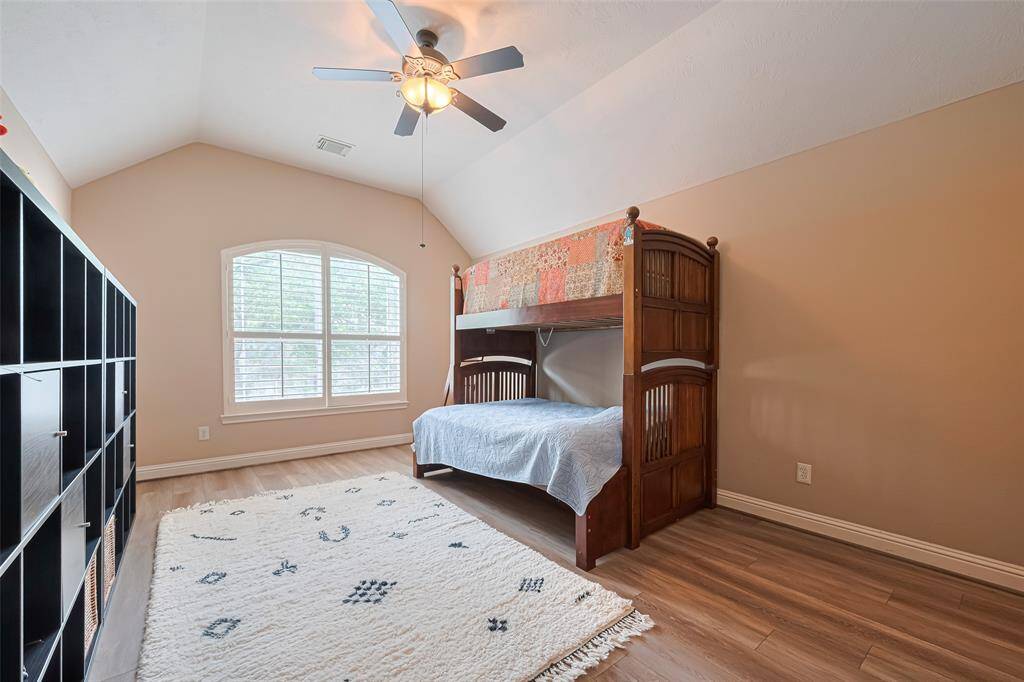 This spacious bedroom features soaring vaulted ceilings and a charming arched window with plantation shutters that invite in beautiful natural light