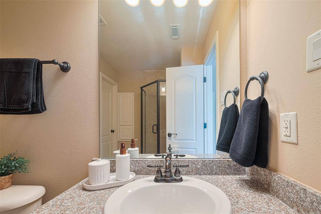 This beautifully maintained bath features granite countertops, a full-size walk-in shower with a framed glass enclosure, and oil-rubbed bronze fixtures that add a touch of sophistication