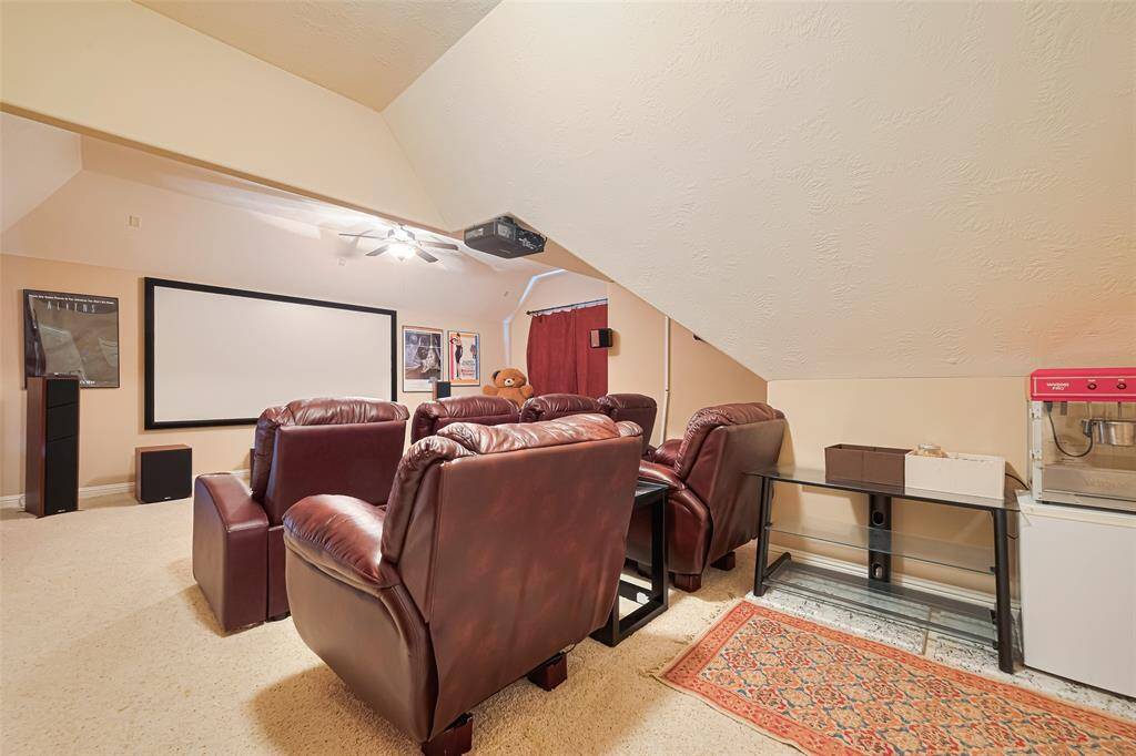 Enjoy cinematic nights in this dedicated media room, fully equipped with tiered leather seating, surround sound speakers, a wall-mounted projector, and a large screen for immersive viewing
