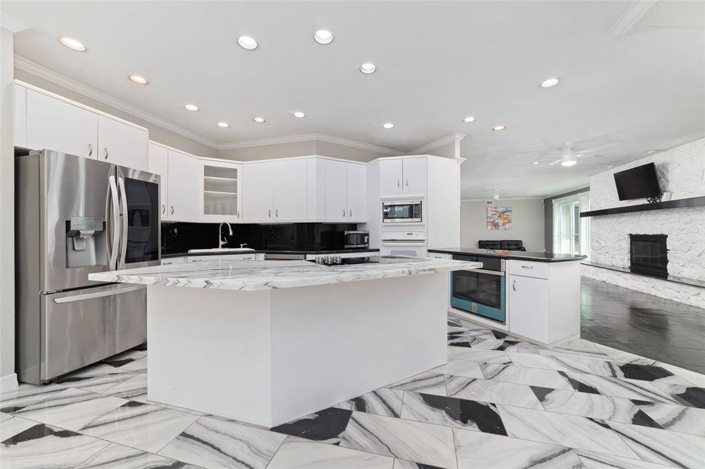 Enjoy this modern kitchen with two ovens (the new stainless steel oven has never been used), a new electric cooktop (which can be replaced with gas if you prefer), an island with a new marble countertop and the stainless refrigerator that is staying.