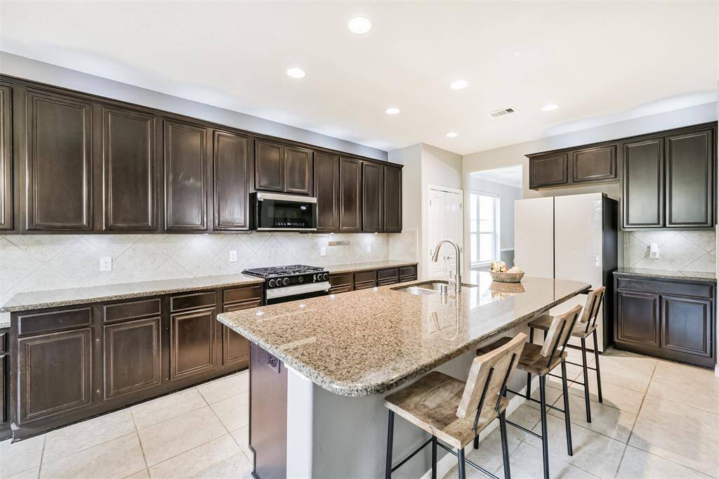 Heading into the kitchen we see the plethora of cabinets providing plenty of storage. A large bar with sink provides additional bar seating.