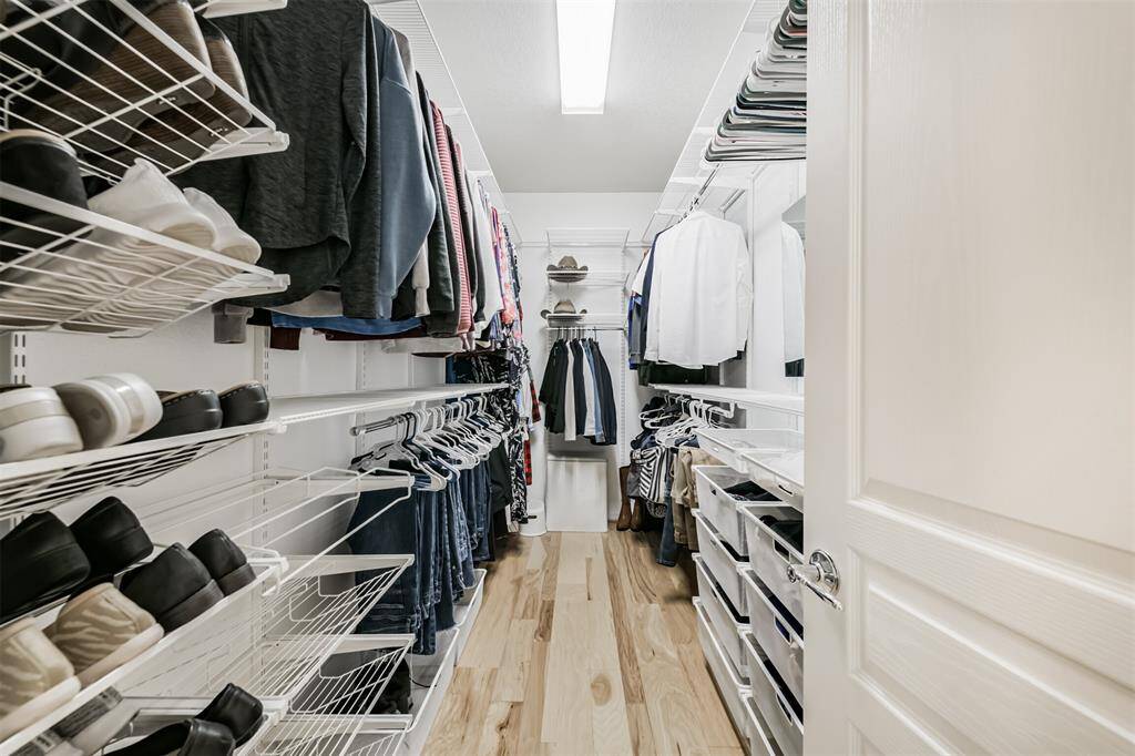 Spacious primary walk-in closet with an organization system to keep your closet looking pristine.