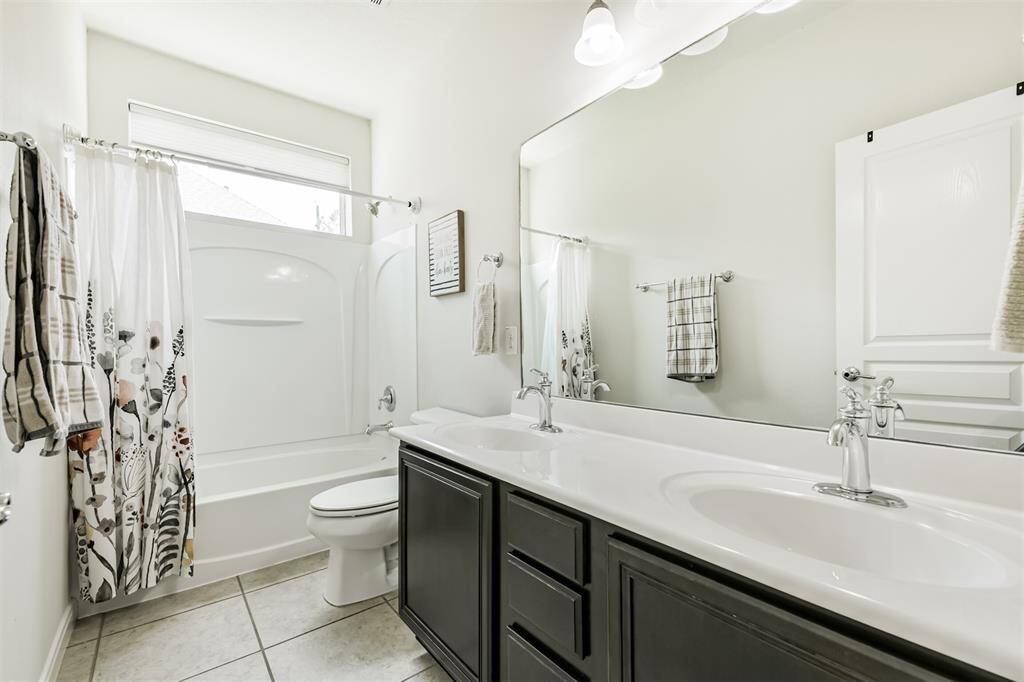 The secondary full-sized bathroom features double sinks and a tub-shower combo.