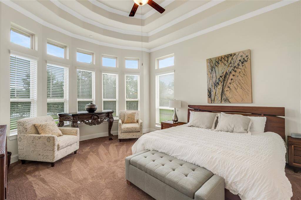 What a dream like primary suite with elegant tray ceiling, rounded out wall of windows overlooking the lake and wait until you see the rest of it.