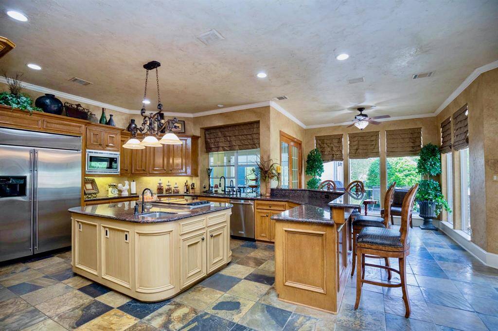 THIS INCREDIBLE KITCHEN IS A COOK'S DREAM! FEATURES INCLUDE STONE FLOORING, STYLISH GRANITE COUNTER TOPS, A WRAP AROUND BREAKFAST BAR, AND OVERSIZED BUILT-IN FRIDGE!