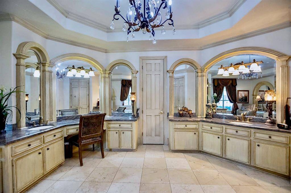 THIS PRIMARY BATH IS COMPLETE WITH CUSTOM WOODWORKING, STONE FLOORING, SPACIOUS STONE COUNTERTOPS, AND ELEGANT LIGHTING!