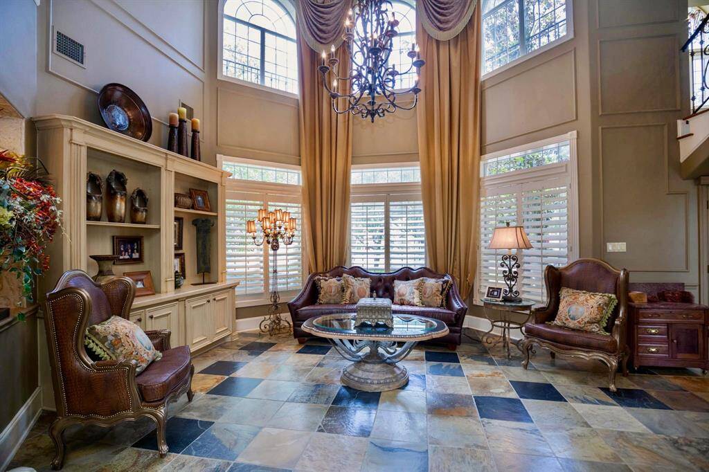 ANOTHER VIEW OF THE ELEGANT FORMAL LIVING AREA! THIS EXQUISITE LIVING ROOM BOASTS SOARING CEILINGS, CUSTOM BUILTINS, DESIGNER LIGHTING, AND FLOOR TO CEILING WINDOWS THAT BRING IN TONS OF NATURAL LIGHT!
