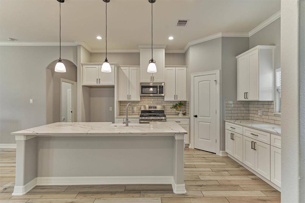 Light and bright chef's kitchen with stainless steel appliances, large block island w/bar seating, and walk-in pantry!