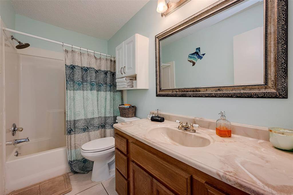 The bathroom is a well-proportioned space, with a shower-tub combo and an overhead cabinet for added storage.