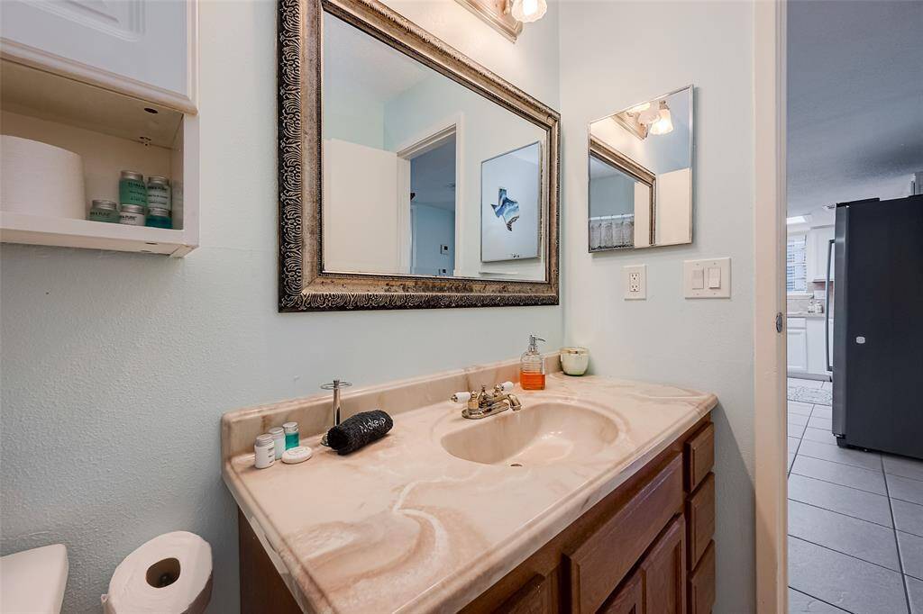 The bathroom also features a spacious vanity with a large mirror, ample lighting, and under-counter storage for organization.