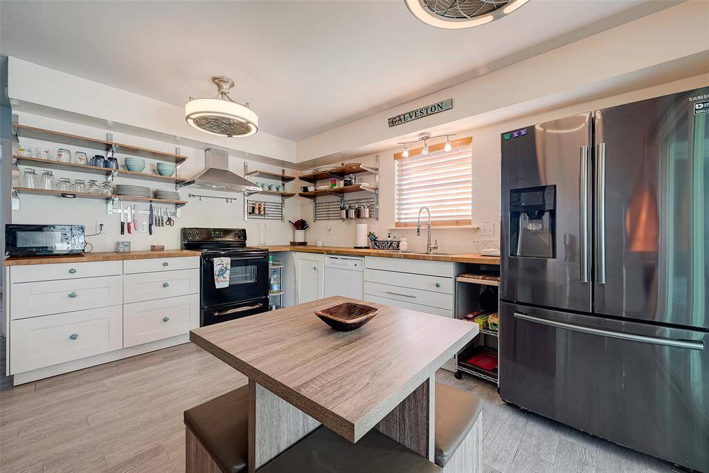 This L-shaped kitchen features ample cabinet space, butcher block countertops, and a dedicated dining area in the center, creating an efficient and inviting workspace.