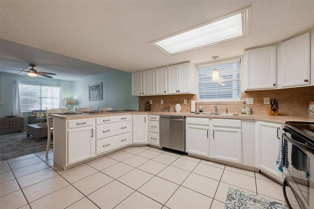 A skylight and a window above the sink flood the kitchen with sunlight, enhancing its fresh and airy feel.