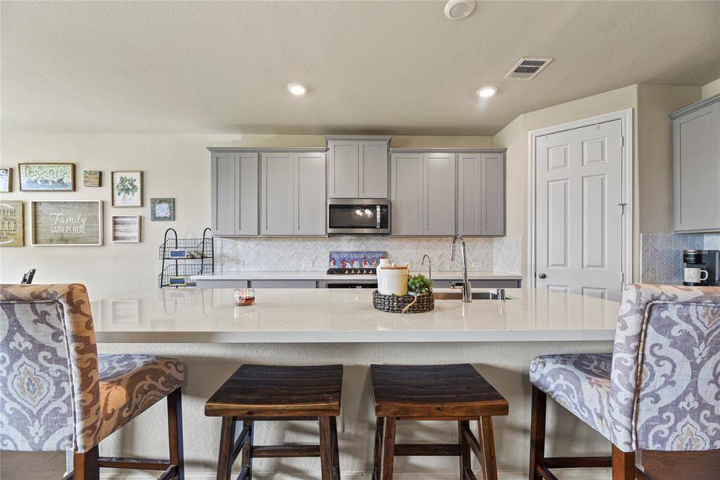 In the heart of the home boasts this chef-inspired kitchen with a LARGE quartz island, beautiful chevron tile backsplash and plenty of 42" Shaker cabinets for ample storage.