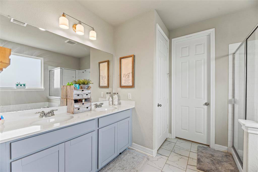 Enjoy relaxing in this inviting en-suite primary bathroom featuring dual sinks and beautiful ceramic tile flooring.