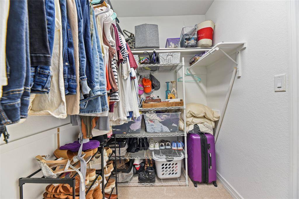 The primary walk-in  closet, just in the bathroom, allows space for many clothing items and storage space up above.