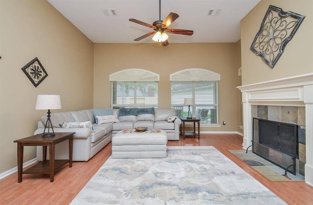 This inviting living room features high ceilings, a cozy fireplace, and large windows that provide ample natural light. The space is tastefully decorated with a neutral color palette.
