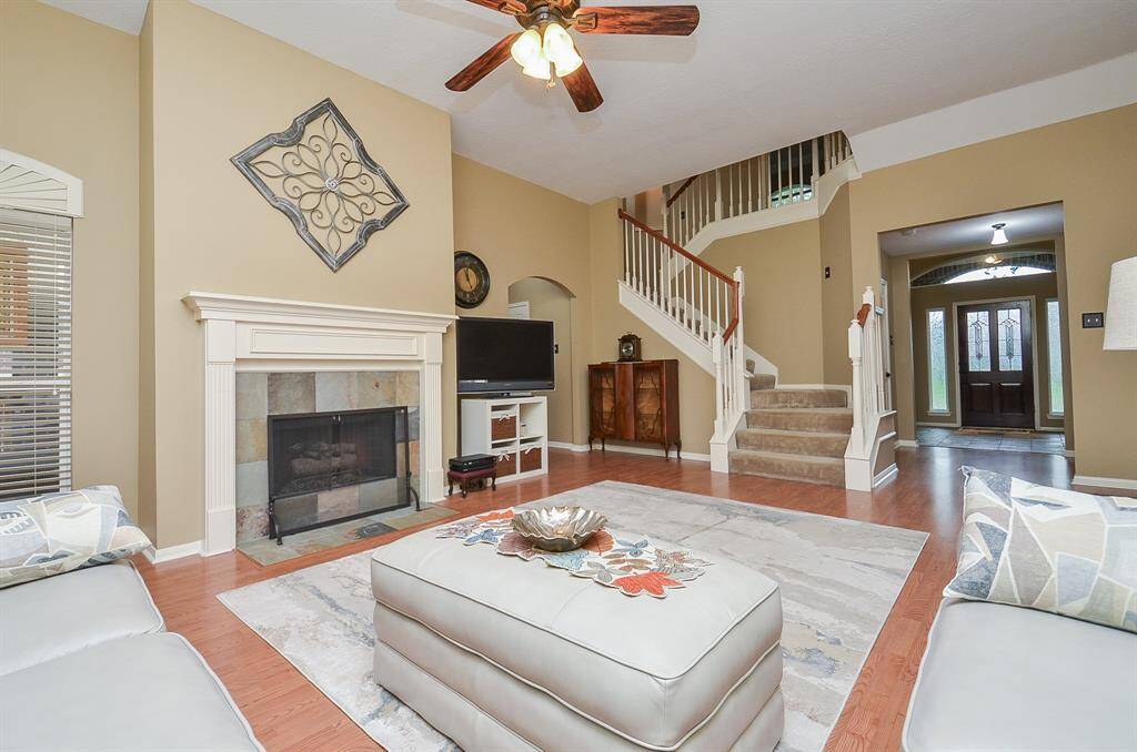 Spacious living room features an elegant staircase, and wood flooring. The open layout is enhanced by natural light, neutral tones creating a welcoming atmosphere ideal for family gatherings.