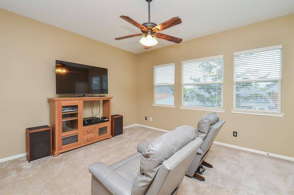 This cozy entertainment room features plush carpet and three large windows for natural light.