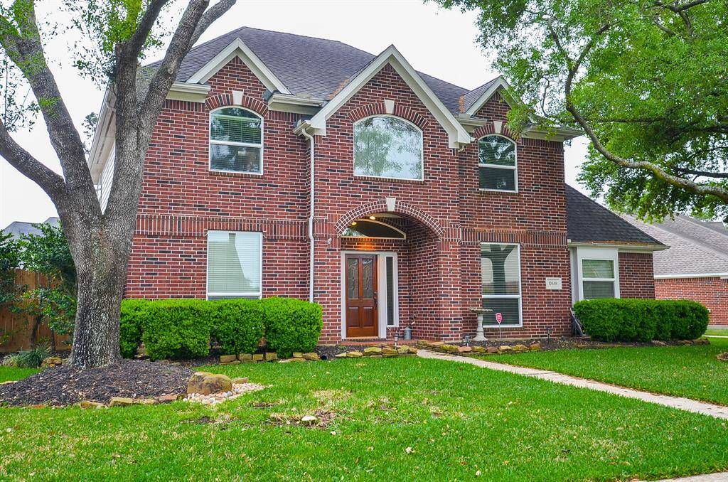 This two-story brick home features a classic design with an arched entryway and large windows.