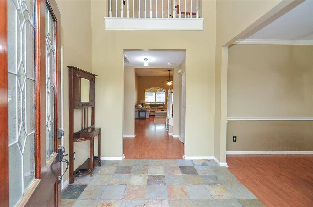 Step into a welcoming foyer with high ceilings, leading into a spacious living area with wood flooring. An open layout and neutral tones create a warm and inviting atmosphere.
