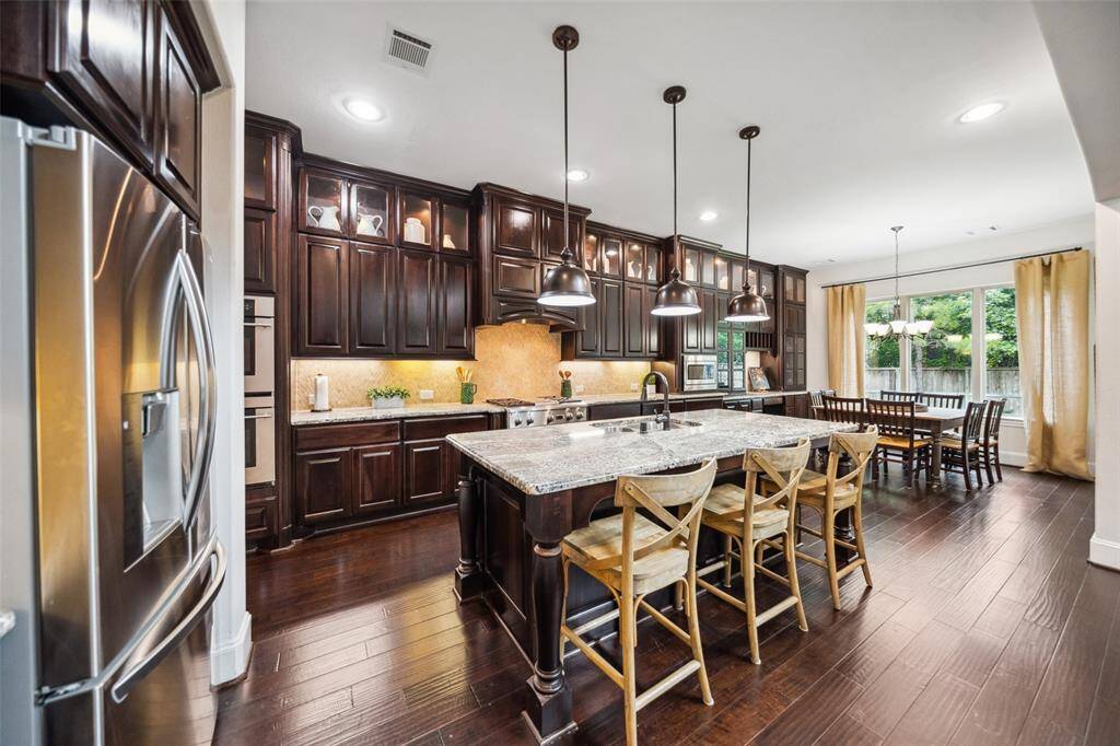 This gourmet kitchen boasts stainless steel appliances, a breakfast bar, elegant pendant lighting, and stunning floor-to-ceiling cabinetry.