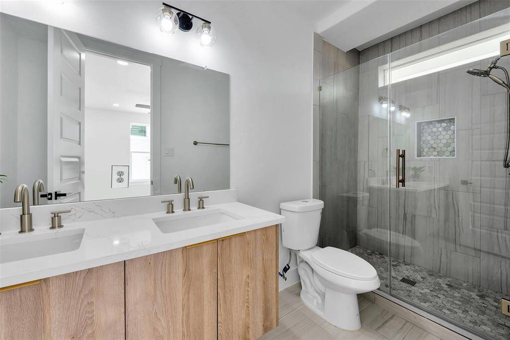 The ensuite bathroom has two sinks and a large glass enclosed tiled shower.
