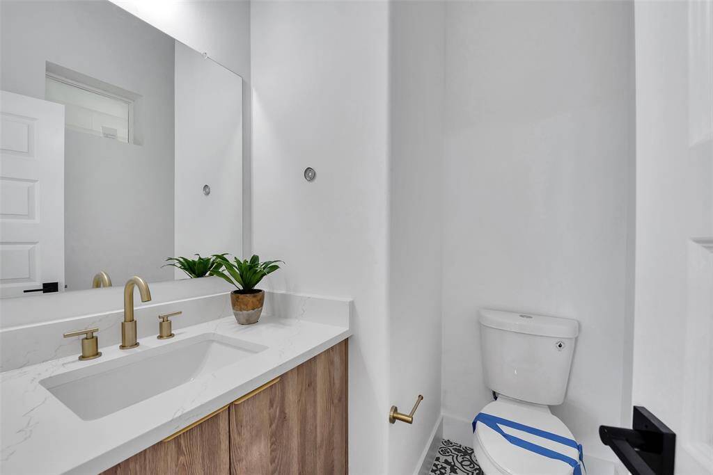 Beautiful brushed brass fixtures grace the half bath and there is plenty of storage under the sink for all your needs.