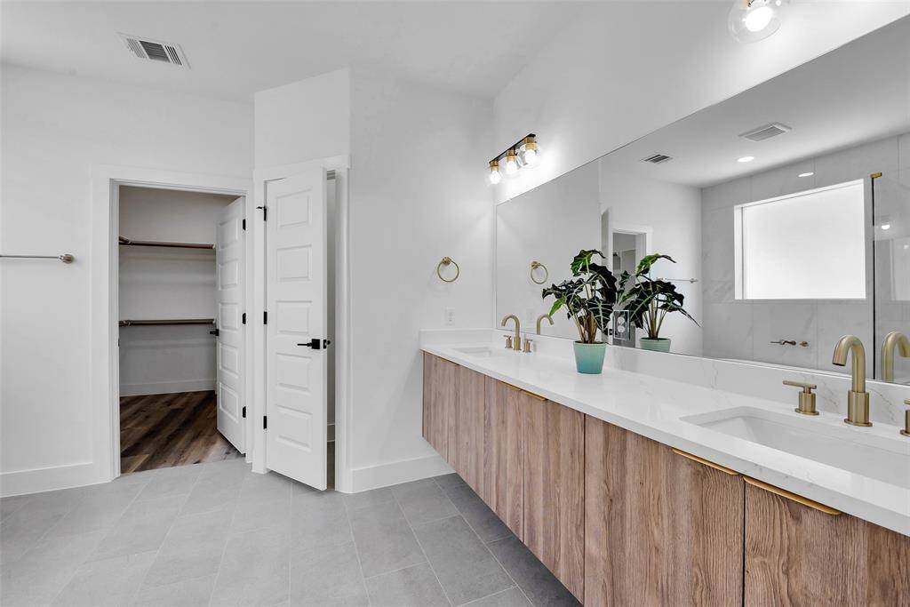 The primary bath features dual sinks, quartz countertop, custom cabinets for all your bath needs, a huge mirror, a walk-in closet, and a water closet.