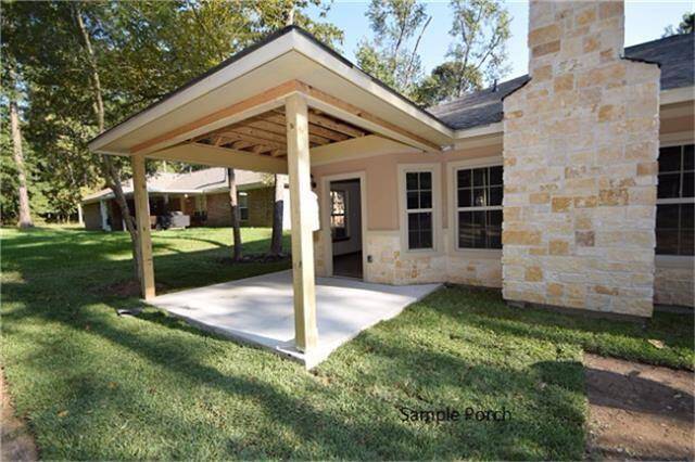 This photo shows a house with a covered porch extension supported by wooden posts, adjacent to a stone or brick  chimney. The porch opens to a grassy backyard, creating a cozy outdoor area.