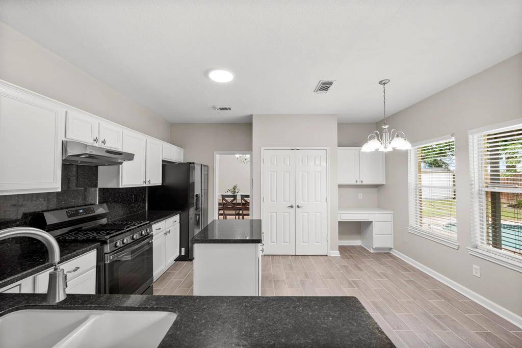 View of the kitchen from the breakfast bar looking at the informal dining area and a nice and practical built-in desk.
