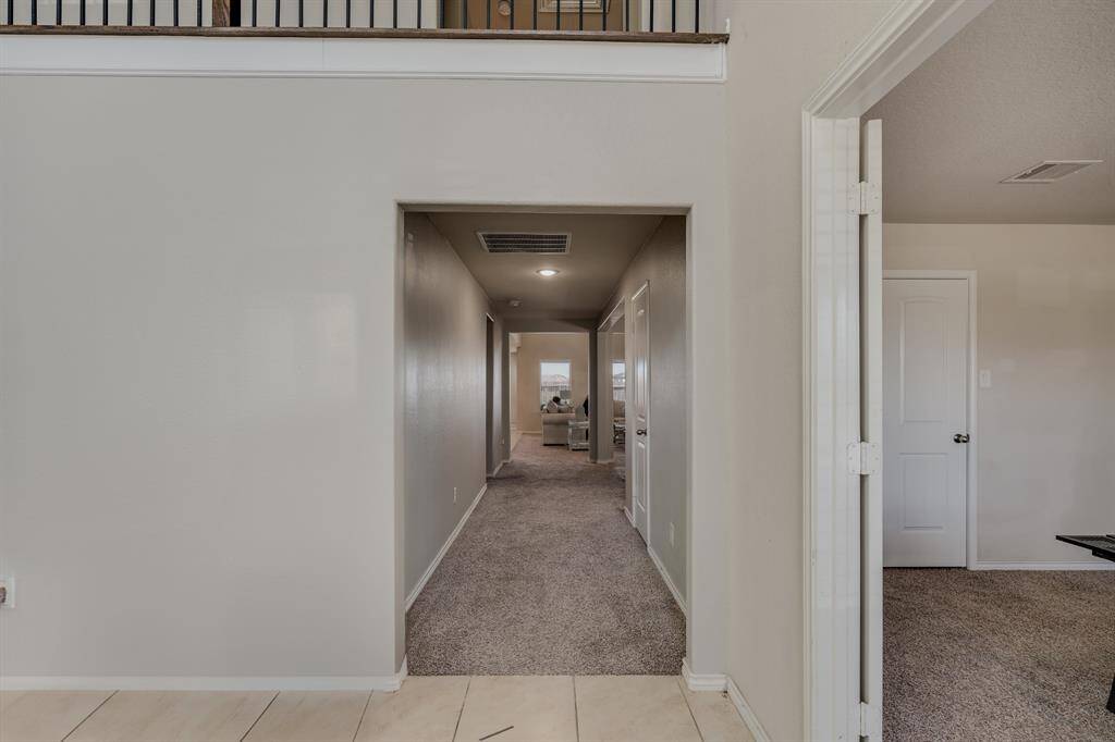 There’s an open doorway on the right, and a glimpse of a second floor with railing above.