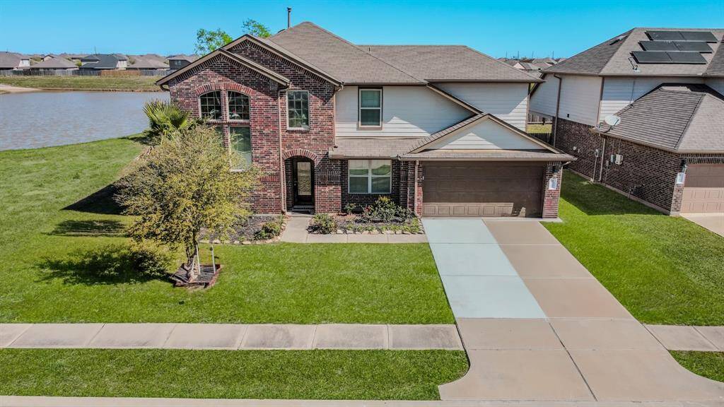 This beautiful two-story brick and siding home features a well-maintained front lawn and a two-car garage. It's located beside a serene lake, offering picturesque water views and a peaceful atmosphere.