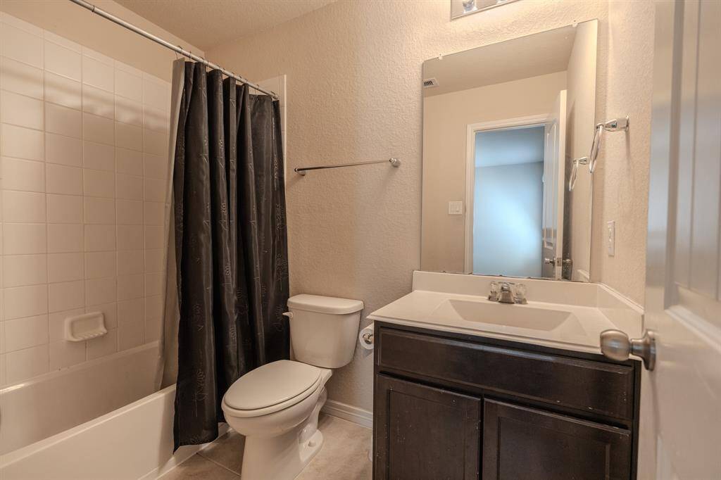This bathroom with a shower-tub combo, a dark wood vanity with a white countertop, and a large mirror.