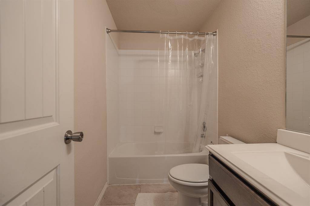 This bathroom features a clean and simple design with a shower-tub combo, a white tiled wall, and a vanity with a mirror. The neutral color palette creates a fresh and inviting atmosphere.