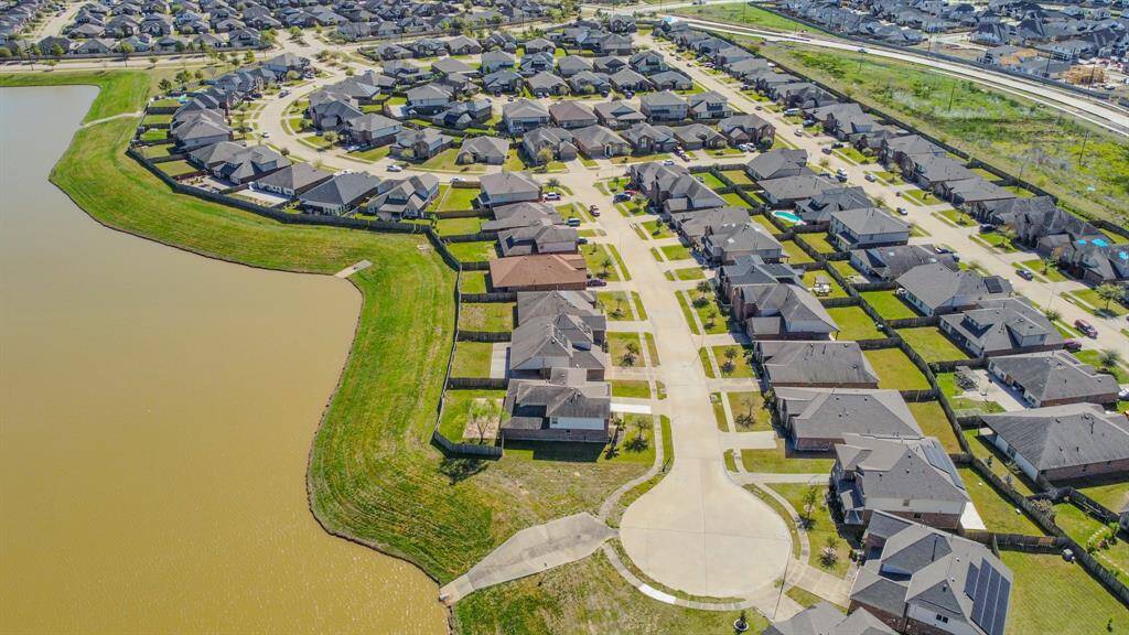 This aerial photo showcases a well-maintained suburban neighborhood with neatly arranged homes and green lawns. The community is situated alongside a large body of water, offering scenic views and a tranquil setting. The streets are clean and well-organized, ideal for families seeking a peaceful residential area.
