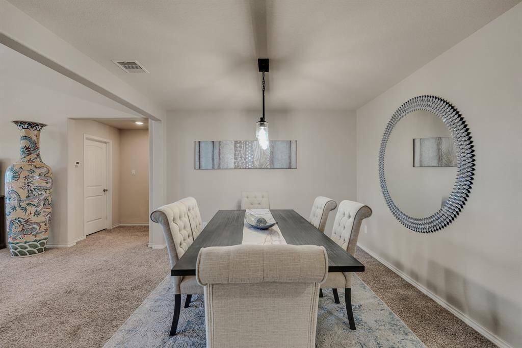 The room is accented with a large decorative mirror, modern artwork, and a statement vase, creating an inviting and elegant atmosphere.