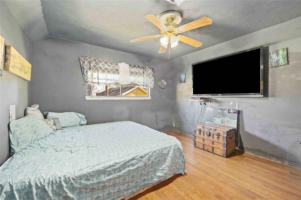 This cozy bedroom features hardwood floors, and a ceiling fan. A window allows natural light, creating a comfortable atmosphere.