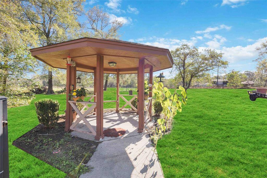 This photo showcases a charming wooden gazebo set in a lush, green backyard. Surrounded by trees, it offers a peaceful outdoor space perfect for relaxation or entertaining.