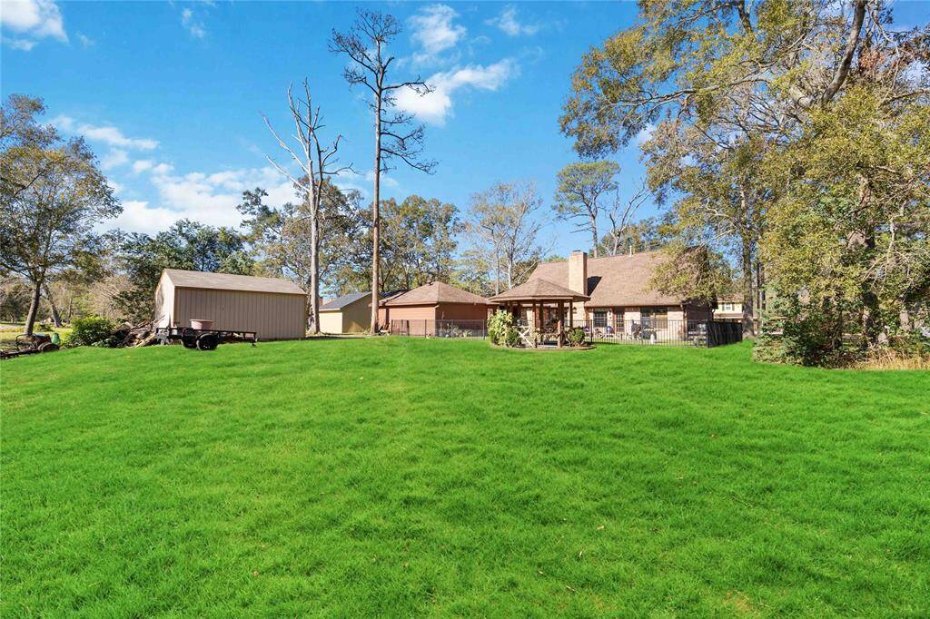 This photo showcases a charming home with a spacious green lawn, surrounded by mature trees. There's a detached garage or shed, and the house features a cozy porch area, perfect for relaxing outdoors.