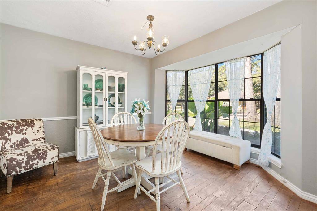 This dining area features light-filled bay windows, while wood flooring enhances the warm, inviting feel.