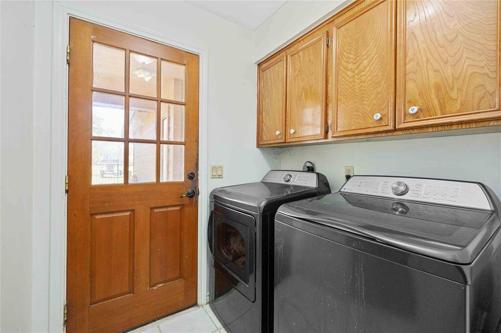 This photo features the laundry room.There's a wooden door with glass panels leading outside, and wooden cabinets above for storage.