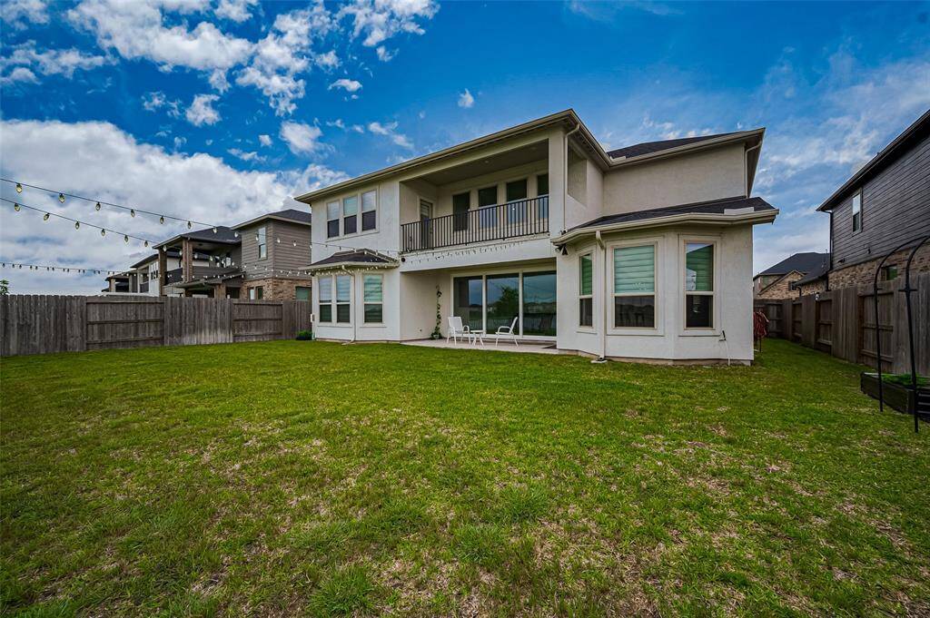 From the backyard, the home’s architectural beauty is on full display. A covered patio offers shade and comfort, while the upstairs balcony above expands your outdoor living space with elevated views of the water.