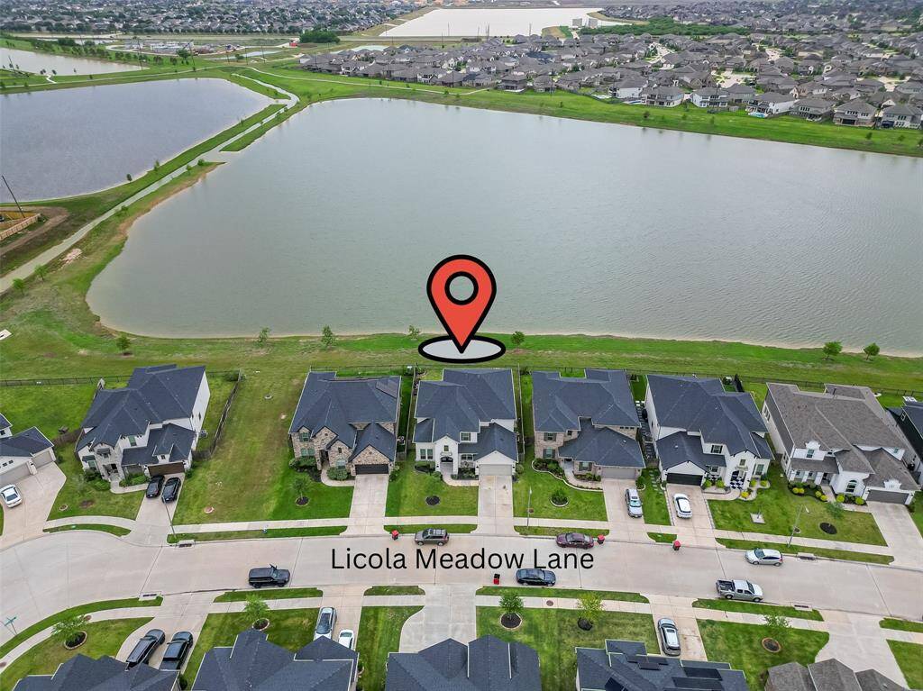 From above, the home's prime waterfront position is unmistakable—nestled in a serene neighborhood with well-kept streets, open grassy areas, and a thoughtful layout that blends suburban tranquility with scenic charm.
