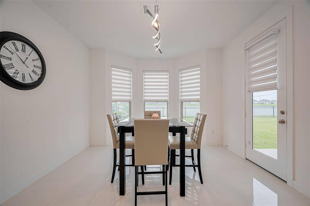 Framed by tall windows and a glass-paneled door leading to the backyard, the dining space is filled with natural light and elevated by a sculptural overhead fixture, making every meal feel special.