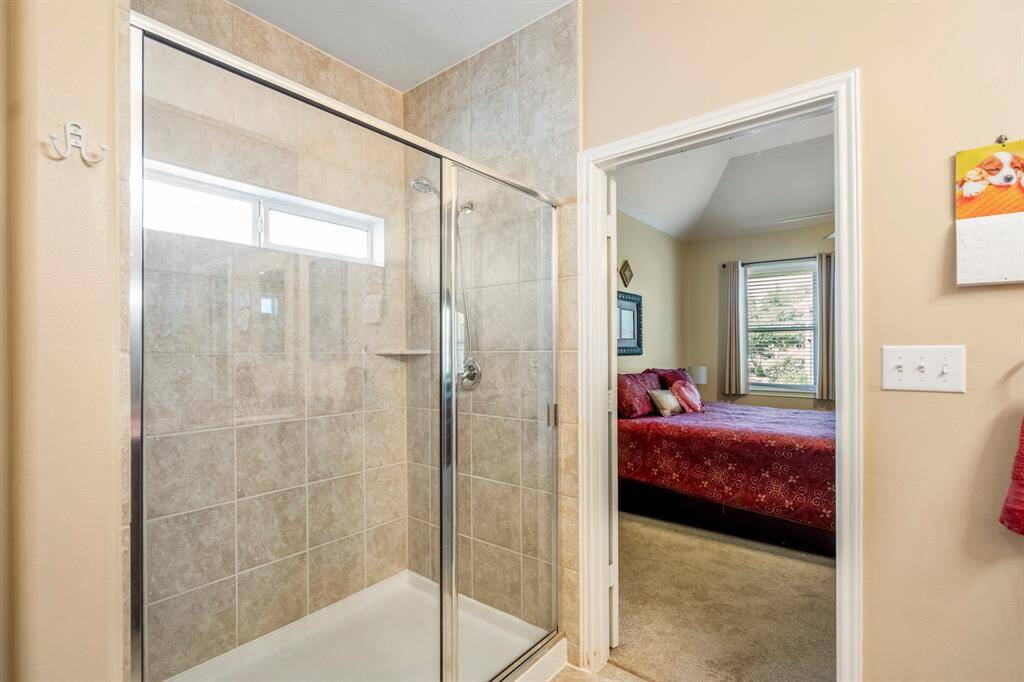 The separate glass enclosed shower offers neutral tones and a window that allows for natural light.