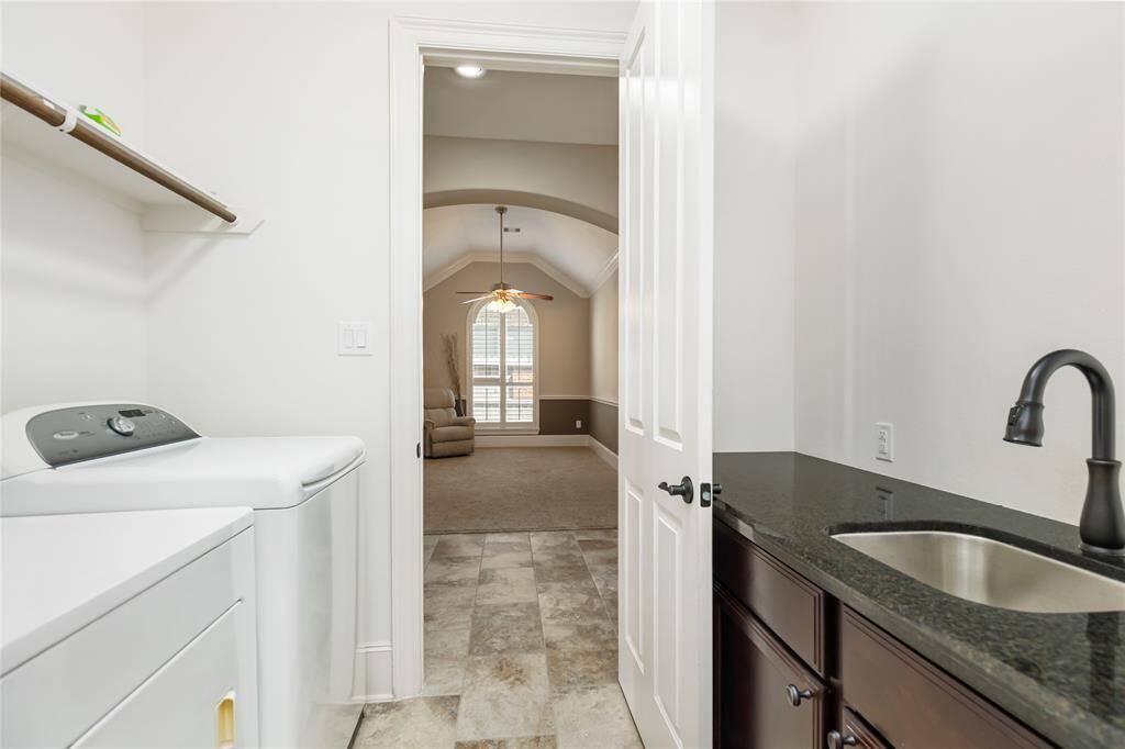 This photo shows a laundry room with a sleek countertop with a sink. It opens into the primary closet.