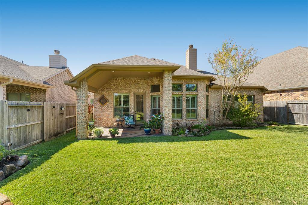 Charming backyard with a well-maintained lawn, a cozy covered patio, and attractive brick exterior. Ideal for relaxation and gatherings.