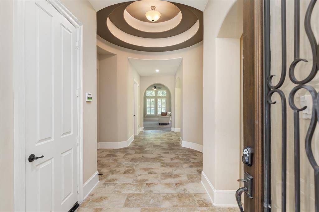 This welcoming entryway features a stylish coffered ceiling, elegant tile flooring, and leads into a bright, open living space with ample natural light.