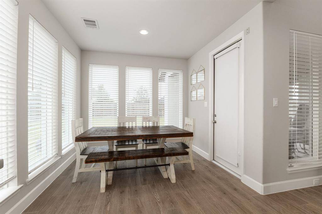 The dining area is surrounded by expansive windows that bathe the space in natural light, while a convenient door to the backyard provides seamless access for outdoor dining and entertaining.