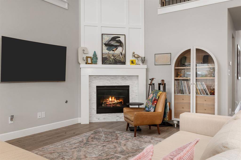 The focal point of the room is a gas log fireplace, beautifully framed with an elegant tile surround, wooden mantel, and detailed moldings that draw the eye upward.
